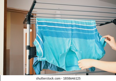 Woman Hanging Her Freshly Washed Clothes On The Clothesline Inside The House