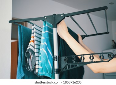 Woman Hanging Her Freshly Washed Clothes On The Clothesline Inside The House