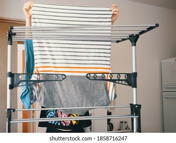 Woman Hanging Her Freshly Washed Clothes On The Clothesline Inside The House