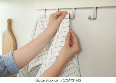 Woman hanging kitchen towel on hook rack indoors, closeup