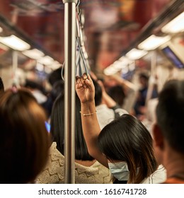 Woman Hanging On To A Strap  In A Crowded Subway Car In Bangkok, Thailand                              