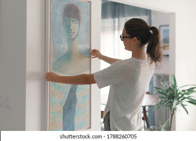 Woman hanging a painting at home and decorating her contemporary living room - Shutterstock ID 1788260705