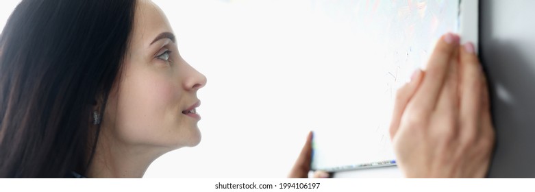 Woman Hanging Picture On Wall At Home