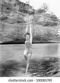 Woman Hanging From Rope Swing Over Water