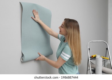 Woman Hanging Stylish Wall Paper Sheet Indoors