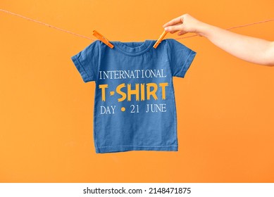 Woman hanging t-shirt on laundry line against color background. International T-Shirt Day