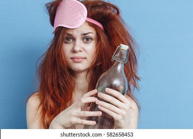 woman hangover on a blue background bottle of alcohol morning