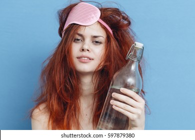 woman hangover on a blue background bottle of alcohol morning