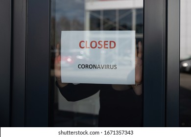 Frau hängt eine Karte mit Informationen über das Geschäft schließen auf einem Schaufenster aufgrund des Coronavirus