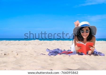 Woman happy smiling and read books on the beach on a beautiful . Pretty girl asian in casual looking away and smile , laughing. The beach beautiful at bright sky