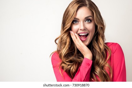 Woman  Happy And Surprised Shouts Holds Cheeks By Hand .Beautiful Girl  With Curly Hair  Pointing To Looking Right . Presenting Your Product. Expressive Facial Expressions Businesswoman  .