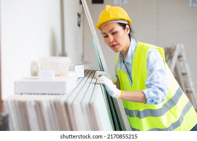 Woman In Hardhat And Yellow Vest Counting Drywall Sheets