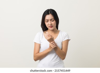 A woman has an inflamed wrist because she is overworked. She massaged her wrists to soothe and relax. Shot on isolated white background. - Shutterstock ID 2157451449