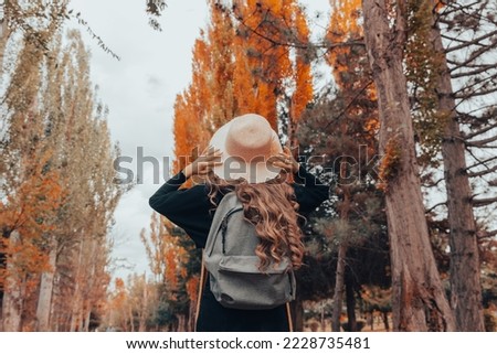 Woman with hat and backpack in autumn forest
