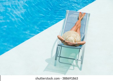 Woman With Hat  Enjoying On Sunbed At Swimming Pool