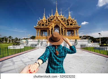 Woman in hat and green checked shirt leading man to the Ananta Samakhom Throne Hall in Thai Royal Dusit Palace, Bangkok, Thailand - Powered by Shutterstock