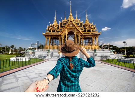 Woman in hat and green checked shirt leading man to the Ananta Samakhom Throne Hall in Thai Royal Dusit Palace, Bangkok, Thailand