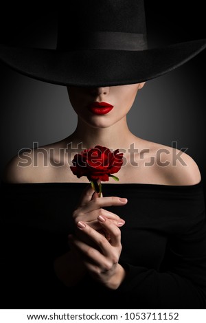 Woman in Hat holding Rose Flower in Hands, Fashion Model Beauty Portrait, Red Lips and Black Wide Brim Hat