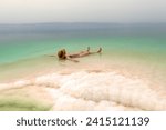 Woman with hat relaxing in salty water of a Dead Sea