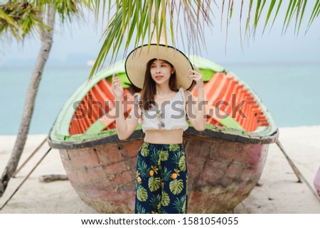 A woman in a hat standing in front of an orange fishing boat