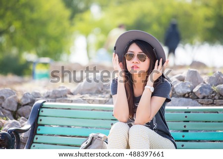 Woman with hat and sunglasses sit on bench