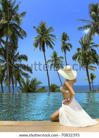Woman in hat and white dress near the swimming pool