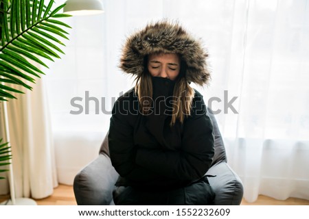 Woman have cold on the sofa at home with winter coat