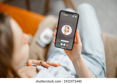 Woman have a high heart rate, call a doctor while sitting on sofa at home. Health and wellness concept. Focus on phone screen.  - Shutterstock ID 1921971440