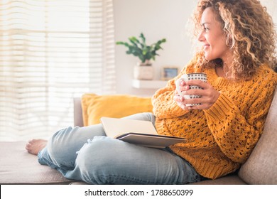 Woman have relax at home with cup of tea and book - reading activity for adult beautiful female people - enjoying quiet lifestyle indoor and long blonde curly hair - happy adult female indoor - people - Shutterstock ID 1788650399