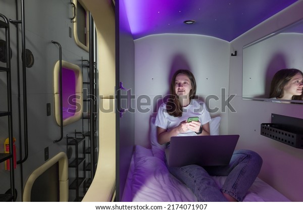 Woman have a\
rest in capsule hotel with\
gadget