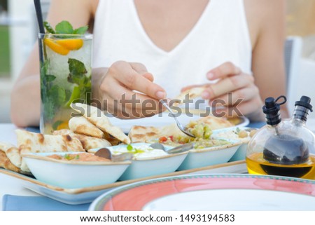 Woman having an appetizer before dinner. Mediterranean mezes served with freshly baked tandoori bread.