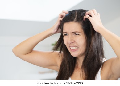 Woman Having A Bad Hair Day Grimacing In Disgust As She Looks In The Mirror And Runs Her Hands Through Her Hair