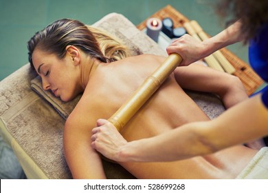 Woman Having Bamboo Stick Massage At Day Spa