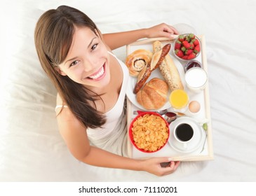 Woman having breakfast in bed. Big continental breakfast. Asian caucasian woman smiling looking at camera. - Powered by Shutterstock