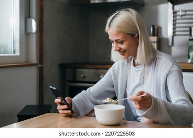 woman having breakfast at home and using mobile phone - Shutterstock ID 2207225503