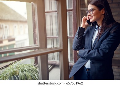 Woman Having Business Conversation On Cell Phone Indoor By Window