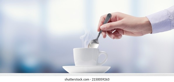 Woman having a coffee break: she is stirring coffee - Powered by Shutterstock