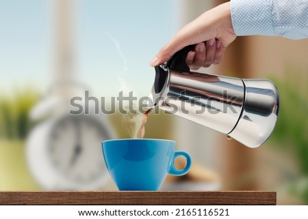 Woman having a coffee break, she is pouring hot coffee in a cup