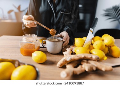 A woman is having a cup of tea on a beautiful morning. Adding honey to the tea with a honey dipper. - Powered by Shutterstock