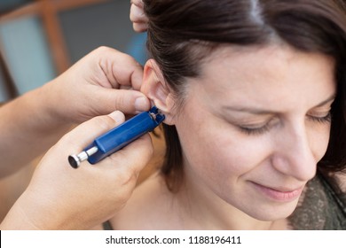 Woman Having Ear Piercing Process With Special Piercing Gun In Beauty Center By Medical Worker, Cropped Close Up View