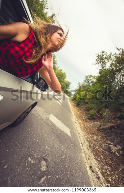Woman having fun with her head out of the car on a\
windy day