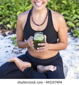 Woman having a green juice outdoors after her yoga practice