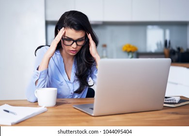 Woman having headache while using laptop at home