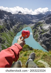 Woman having a healthy meal after long trekking in the mountains. The girl it is dressed with sportwear and it is in front of a blue lake at the summit of the mountain.