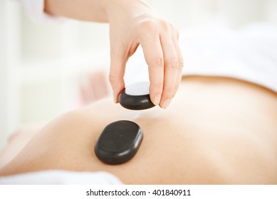 Woman Having Hot Stones On Her Back In Spa Salon