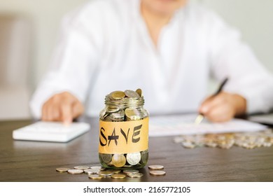 woman having ideas for saving money, She is pressing the calculator and picking up a coin, saving money or savings concept.