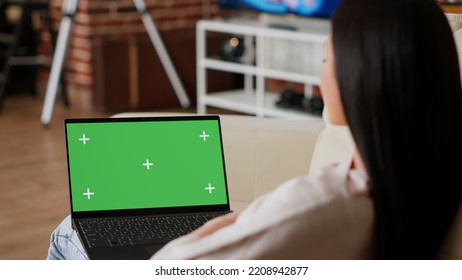 Woman Having Laptop With Green Screen Chroma Key Template Display While Sitting On Sofa At Home. Person With Computer Having Mockup Isolated Background While In Apartment.