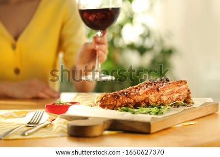 Woman having lunch in restaurant, focus on delicious roasted ribs