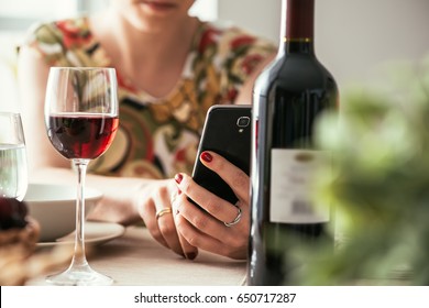 Woman having lunch at the restaurant and using a wine app with his smartphone, she is scanning the wine bottle label - Powered by Shutterstock