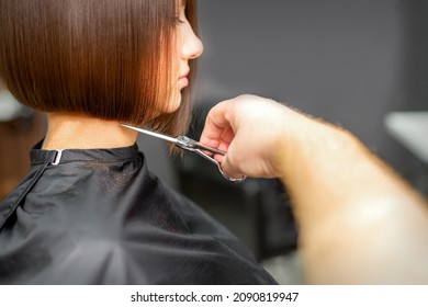 Woman Having A New Haircut. Male Hairstylist Cutting Brown Hair With Scissors In A Hair Salon